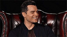 a man is sitting in a leather chair laughing and smiling .