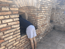 a man leaning against a brick wall with his legs crossed