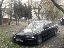 a black car is parked on the side of a dirt road in a park .