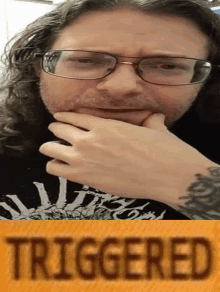 a man with glasses and a tattoo on his arm has the word triggered on the bottom