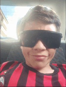 a boy wearing sunglasses and a red and black shirt with the letter a on it