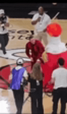 a group of people are standing on a basketball court with a coca cola mascot .