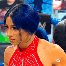 a woman with blue hair is wearing a red dress with a w logo on the back