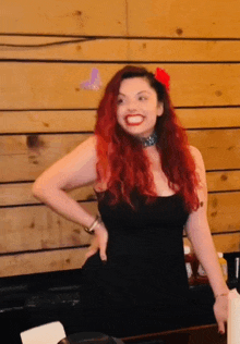 a woman with red hair wearing a choker and a black dress smiles