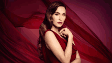 a woman in a red dress is standing in front of a red curtain