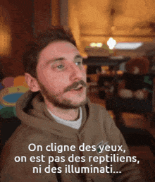 a man with a beard says on cligne des yeux on est pas des reptiliens ni des illuminati