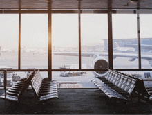 a row of chairs in an airport waiting area with a view of an airplane on the tarmac