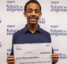 a young man in a blue shirt is holding a check in front of a wall .