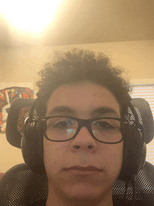 a young man wearing glasses and headphones is sitting in a chair