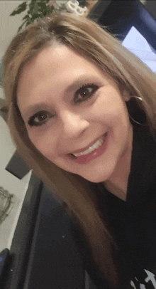 a woman wearing a black shirt with the word t on it smiles for the camera