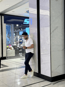 a man leans against a wall in front of a store with the letter s on it