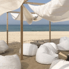 white bean bag chairs on a beach under a white canopy