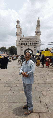 a man is standing in front of a mosque with a yellow truck in the background