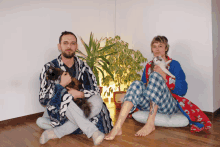 a man and a woman sitting on the floor with a cat