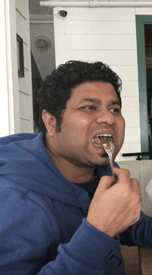 a man wearing a blue sweatshirt is eating with a fork