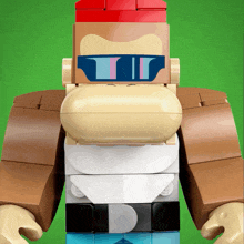 a lego gorilla wearing sunglasses and a red hat on a green background