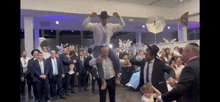 a man in a hat is being lifted in the air by a group of people