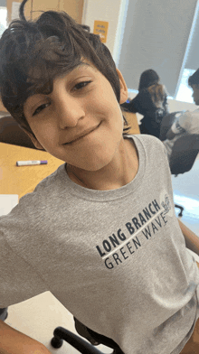 a young boy is wearing a long branch green wave shirt