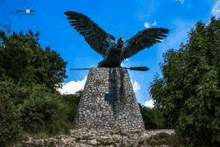 a statue of a bird with a sword in its beak is sitting on top of a stone pillar .