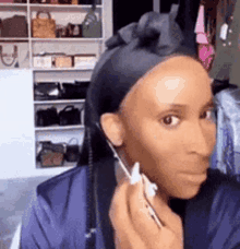 a woman is applying makeup to her face while wearing a headband .