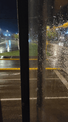 a view of a rainy street through a window with a tree in the foreground