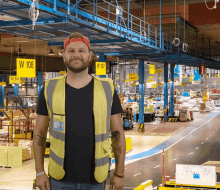 a man in a yellow vest stands in a warehouse with a yellow sign that says w 108 on it