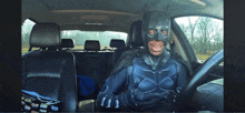 a man in a batman costume driving a car