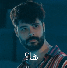 a man with a beard is wearing a striped shirt with arabic writing on it .