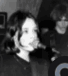 a black and white photo of a woman talking into a microphone .