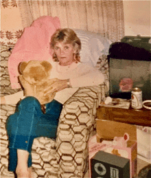 a woman sits in a chair with a teddy bear and a box that says ' o ' on it