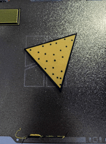 a yellow triangle with black dots on it is on a black surface