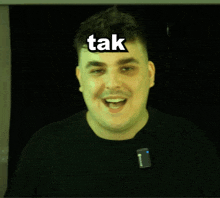 a man with a microphone on his neck has the word tak on his forehead