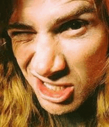 a close up of a man 's face with his mouth open and a beard .