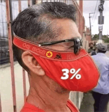 a man wearing a red face mask with a 3% sticker on it .