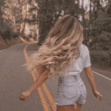 a woman with long blonde hair is walking down the road