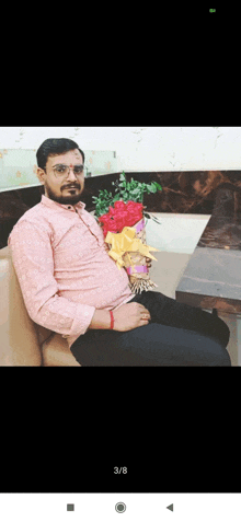 a man is sitting on a couch with a bouquet of flowers in his lap .