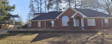 a large red brick house with a black roof and white trim