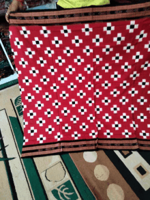 a red cloth with black and white squares on it is laying on a rug