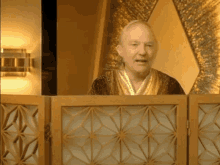 a man in a robe stands behind a wooden partition