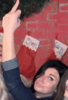 a woman is giving a thumbs up in front of a christmas stocking that says glen