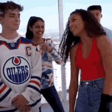 a group of young people are standing next to each other and one of them is wearing a hockey jersey .