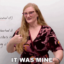 a woman wearing glasses stands in front of a white board with the words it was mine written on it