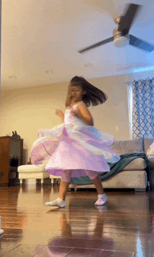 a little girl in a purple dress is spinning in a living room