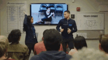 a man and a woman are standing in front of a group of people in front of a whiteboard that says team curry