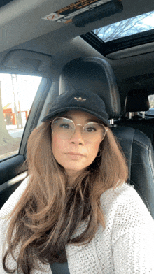 a woman wearing glasses and a black hat is sitting in the back seat of a car