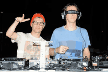 two men wearing behringer headphones are standing in front of a mixer