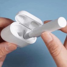 a person is holding a cigarette in their hand next to an airpod case