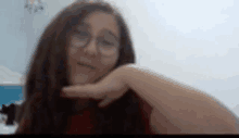 a girl wearing glasses is making a selfie with her hand on her face .