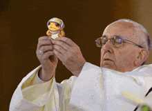 a priest is holding a toy frog with a helmet on it