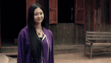 a woman with long black hair wearing a purple sweatshirt